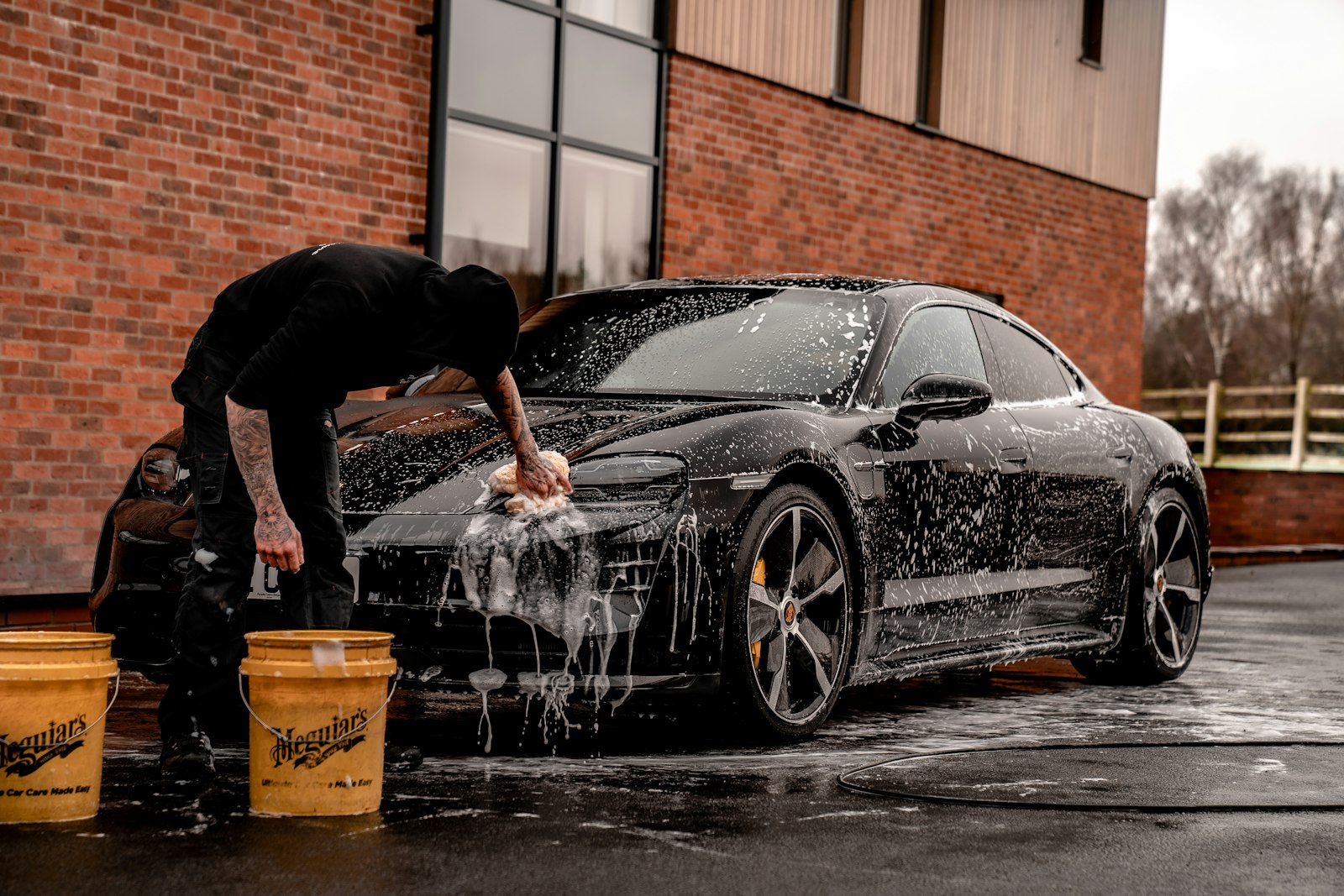 Detailer hand-washing a black sports car before coating