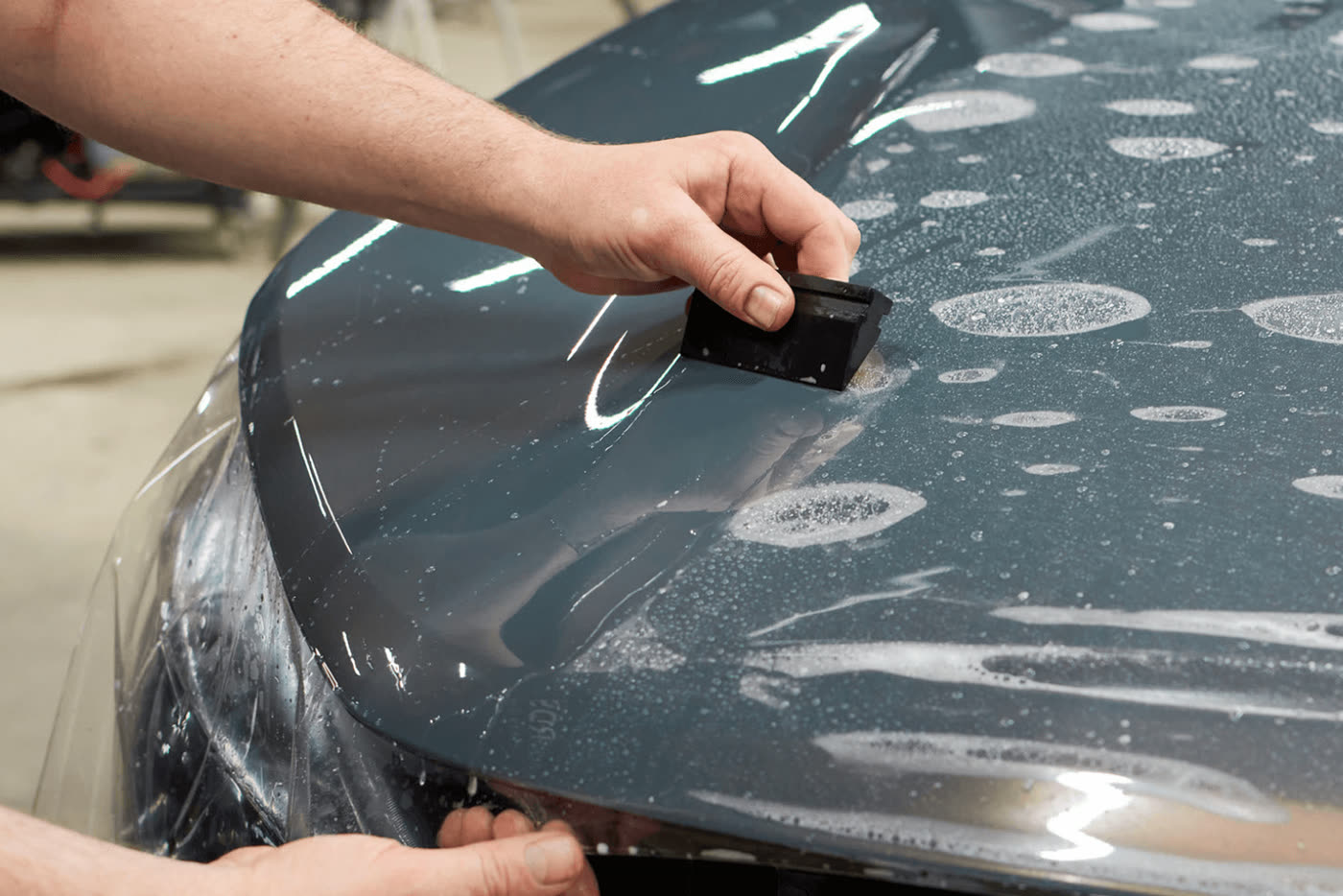 Squeegee smoothing paint protection film onto a hood