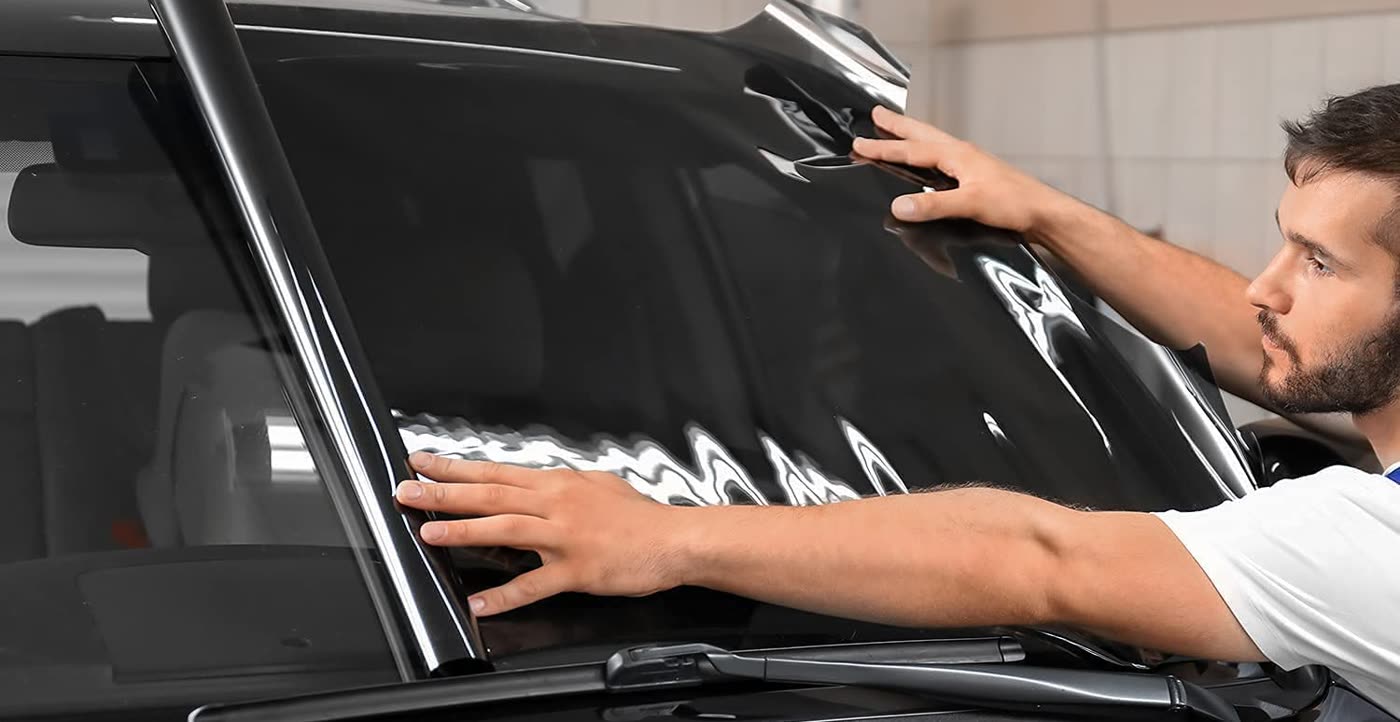 Installer fitting window tint film on a windshield